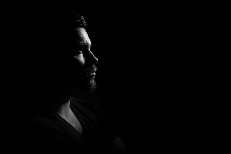 grayscale photo of man in black v neck shirt with black background