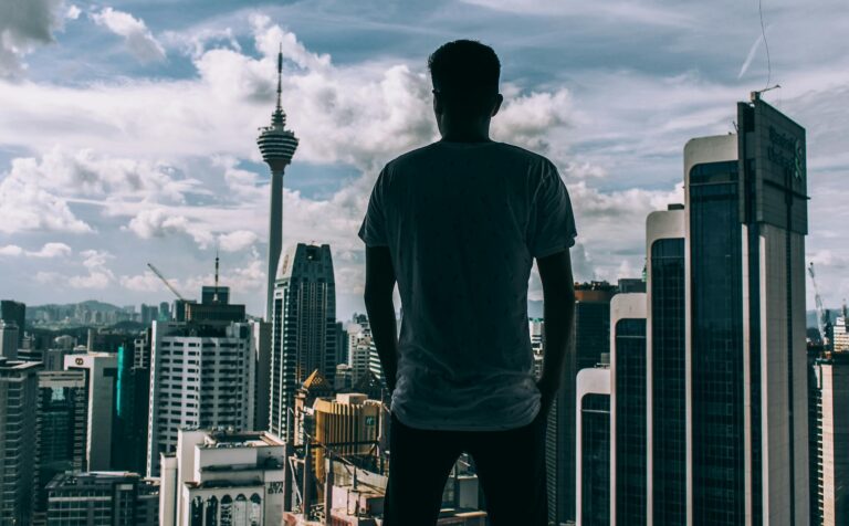 man standing while facing concrete buildings